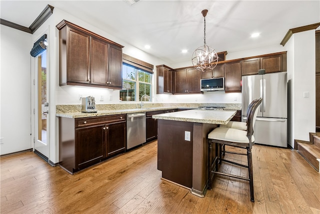 kitchen featuring light wood-type flooring, appliances with stainless steel finishes, pendant lighting, and a kitchen island