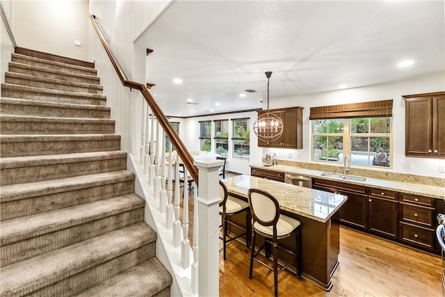 kitchen with hanging light fixtures, a breakfast bar area, sink, light hardwood / wood-style floors, and a center island