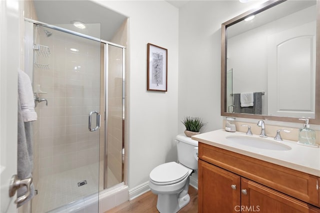 bathroom featuring an enclosed shower, vanity, toilet, and hardwood / wood-style flooring