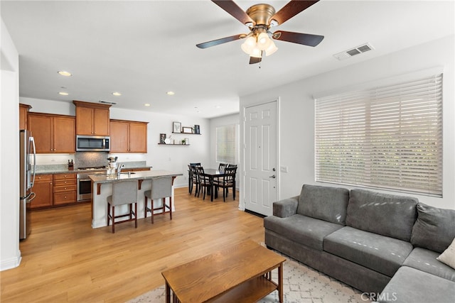 living room with ceiling fan, light hardwood / wood-style flooring, and sink