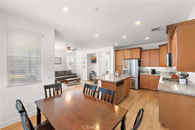 dining room with ceiling fan, sink, and light hardwood / wood-style flooring