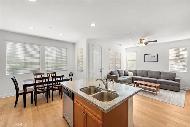 kitchen with ceiling fan, dishwasher, sink, a center island with sink, and light wood-type flooring