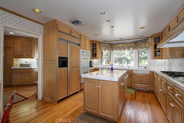 kitchen featuring a center island, paneled fridge, white double oven, light hardwood / wood-style floors, and decorative backsplash