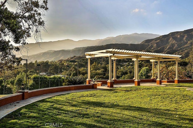 surrounding community with a pergola, a mountain view, and a lawn