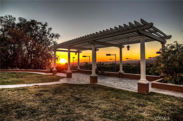 patio terrace at dusk featuring a yard and a pergola