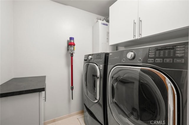 clothes washing area with light tile patterned flooring, cabinets, independent washer and dryer, and water heater