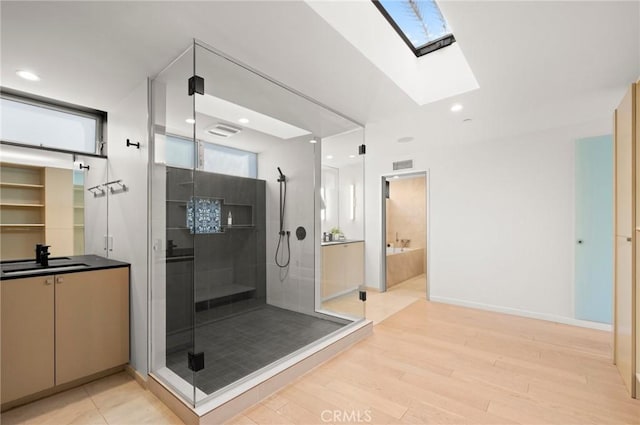 bathroom with a skylight, sink, wood-type flooring, and independent shower and bath