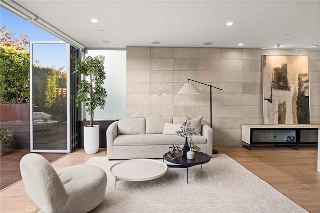 living room with floor to ceiling windows, light wood-type flooring, and tile walls