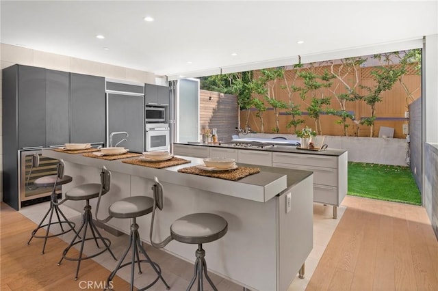 kitchen featuring light wood-type flooring, a breakfast bar, stainless steel appliances, white cabinets, and a kitchen island