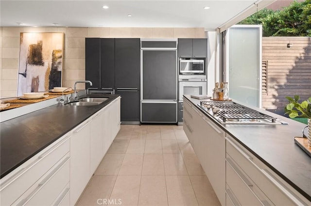 kitchen featuring white cabinets, appliances with stainless steel finishes, light tile patterned floors, and sink