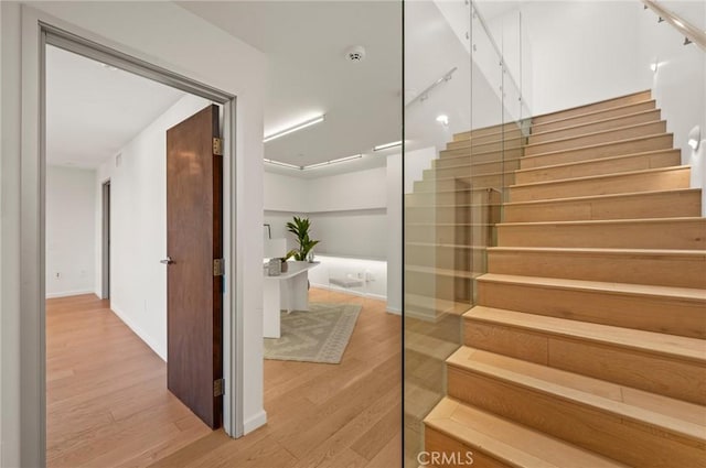 stairway with hardwood / wood-style flooring and track lighting