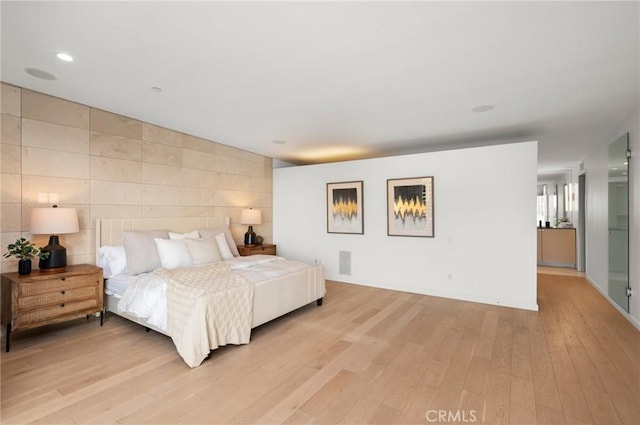 bedroom featuring light hardwood / wood-style floors and tile walls