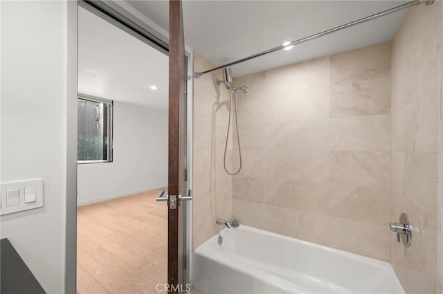 bathroom with hardwood / wood-style floors and tiled shower / bath combo