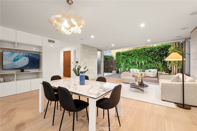 dining area featuring floor to ceiling windows, light hardwood / wood-style floors, and a healthy amount of sunlight