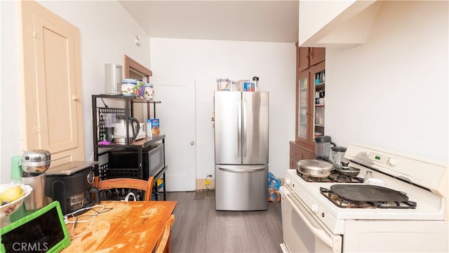 kitchen with dark hardwood / wood-style flooring, white cabinets, stainless steel fridge, and white gas stove