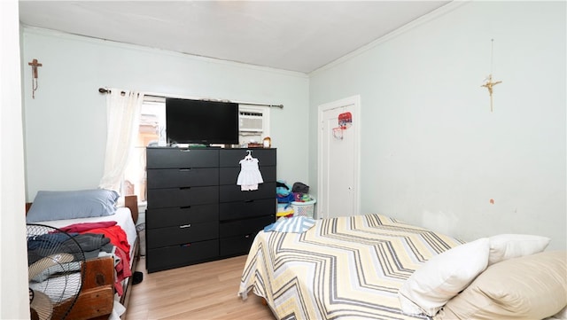 bedroom featuring an AC wall unit, crown molding, and light wood-type flooring