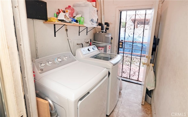 clothes washing area featuring gas water heater, washing machine and dryer, and light tile patterned floors