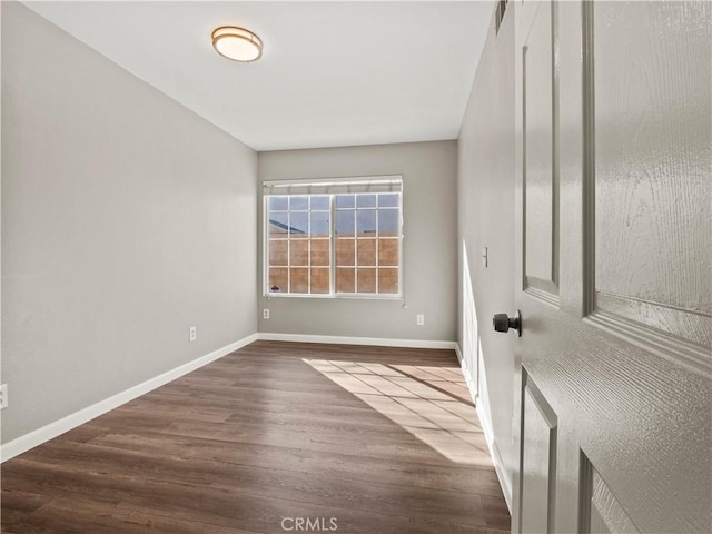 spare room with dark wood-style flooring and baseboards