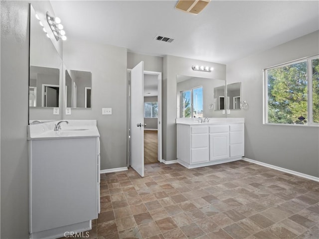 full bathroom with two vanities, visible vents, stone finish flooring, a sink, and baseboards