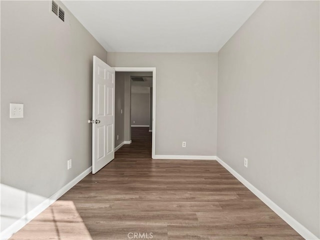 unfurnished room with wood finished floors, visible vents, and baseboards