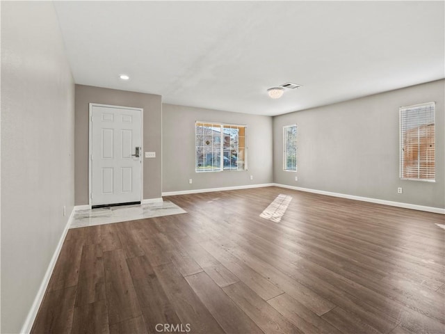 foyer entrance with baseboards, visible vents, and dark wood finished floors