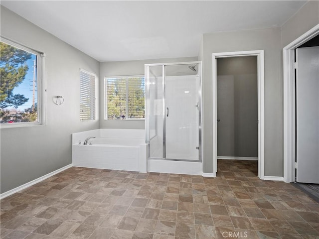 full bath with a shower stall, baseboards, and a bath