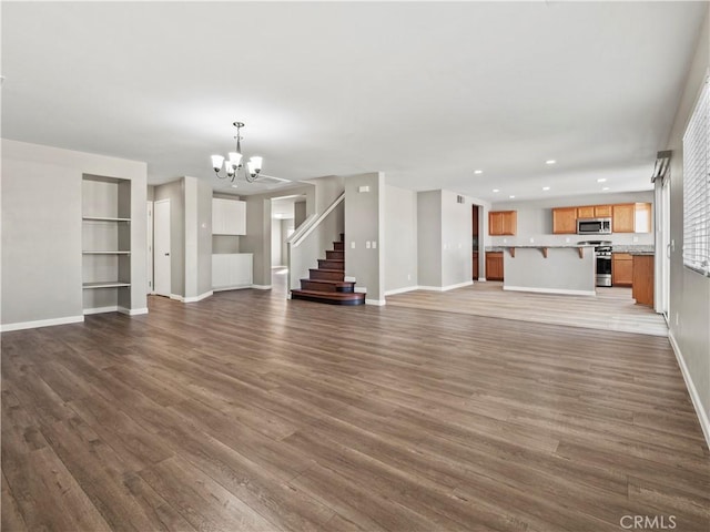 unfurnished living room featuring baseboards, stairway, dark wood-style flooring, a chandelier, and recessed lighting