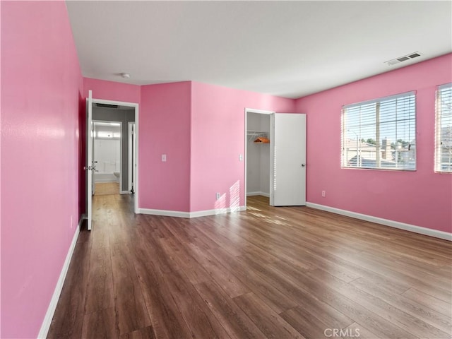 unfurnished bedroom featuring wood finished floors, visible vents, and baseboards