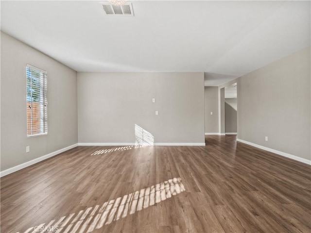 unfurnished room featuring baseboards, visible vents, and wood finished floors