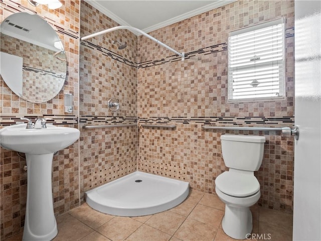 bathroom featuring tile patterned flooring, toilet, tile walls, ornamental molding, and a stall shower