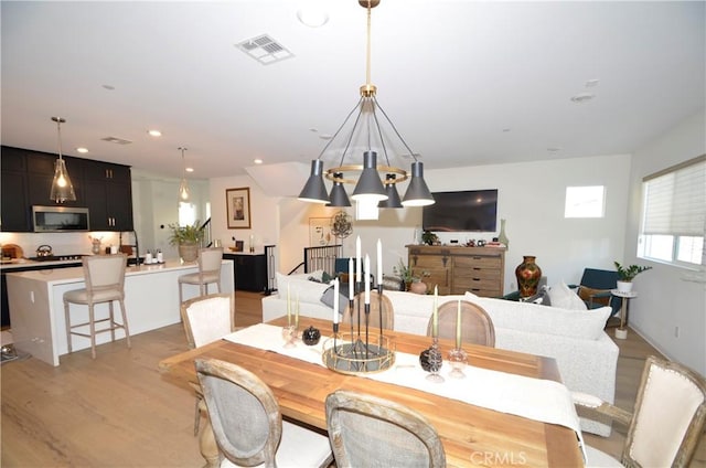 dining space with light hardwood / wood-style flooring and a chandelier