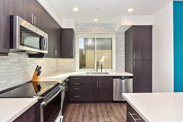 kitchen with dark hardwood / wood-style flooring, dark brown cabinets, sink, decorative backsplash, and appliances with stainless steel finishes