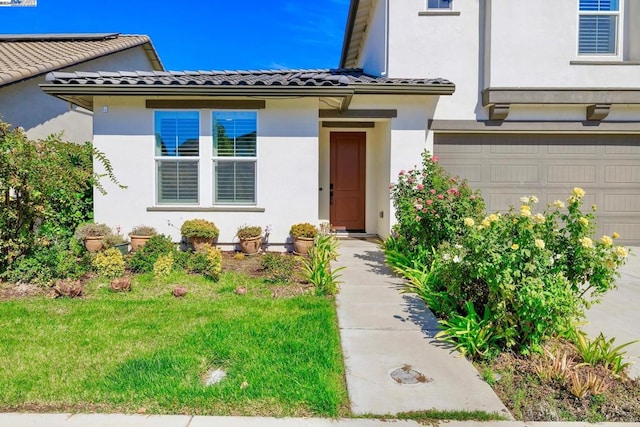 entrance to property with a garage and a lawn