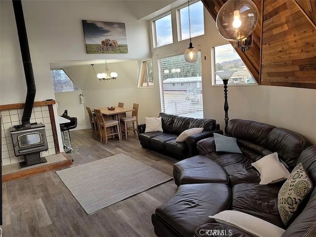 living room with high vaulted ceiling, a wood stove, and wood-type flooring