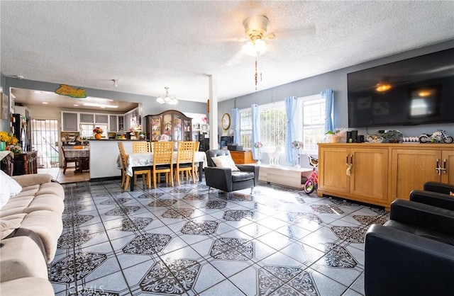 living room featuring ceiling fan with notable chandelier, a textured ceiling, and tile patterned flooring