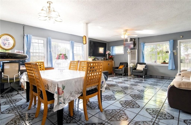 dining area featuring ceiling fan with notable chandelier and a textured ceiling