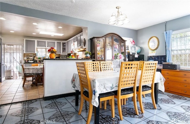 dining space with a chandelier, a textured ceiling, and dark tile patterned floors