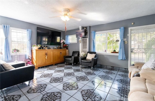 living room with a textured ceiling, ceiling fan, and a healthy amount of sunlight