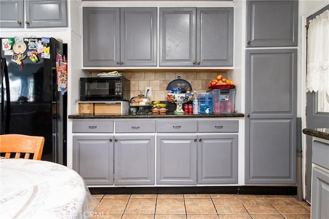 kitchen with gray cabinets, decorative backsplash, light tile patterned floors, and black appliances