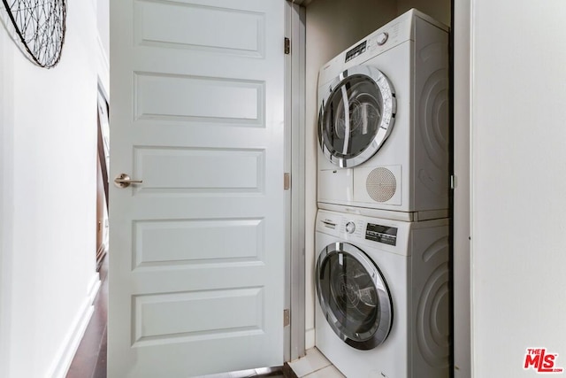 laundry area with light tile patterned floors and stacked washer and dryer