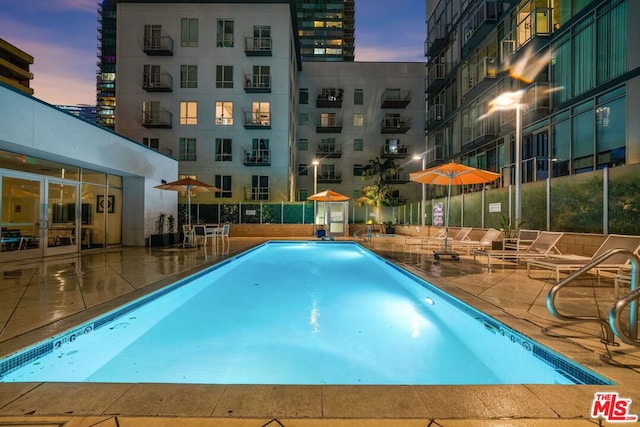 pool at dusk with a patio area