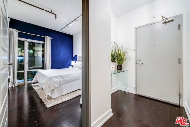 bedroom featuring dark hardwood / wood-style floors and track lighting