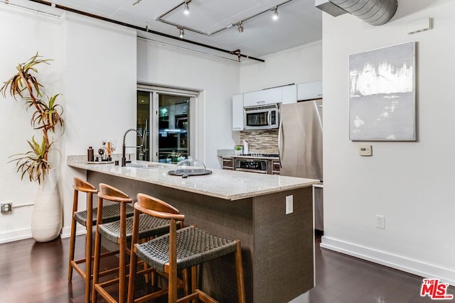 kitchen with dark hardwood / wood-style floors, a breakfast bar, stainless steel appliances, white cabinets, and sink