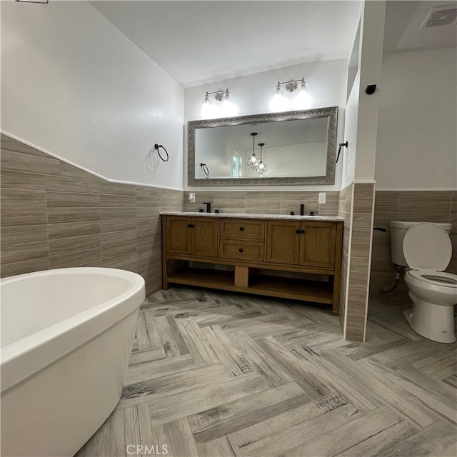 bathroom featuring vanity, toilet, tile walls, and a tub