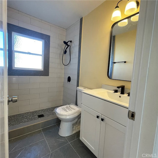 bathroom featuring vanity, toilet, tile patterned floors, and tiled shower