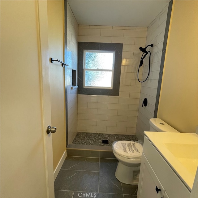 bathroom featuring vanity, toilet, tile patterned floors, and a tile shower