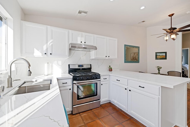 kitchen with sink, stainless steel gas range oven, vaulted ceiling, and kitchen peninsula