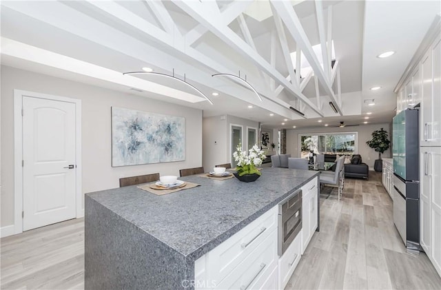 kitchen featuring white cabinetry, a center island, light hardwood / wood-style floors, and appliances with stainless steel finishes