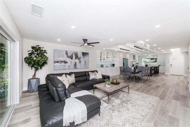 living room featuring ceiling fan, a healthy amount of sunlight, and light wood-type flooring