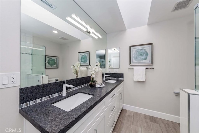 bathroom with hardwood / wood-style flooring, vanity, toilet, and walk in shower